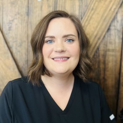 Sydney Maltba, employee at Greatest Potential Chiropractic, headshot in front of a wooden wall